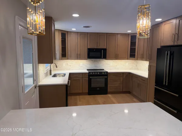 a large kitchen with stainless steel appliances a large counter top a stove and a refrigerator