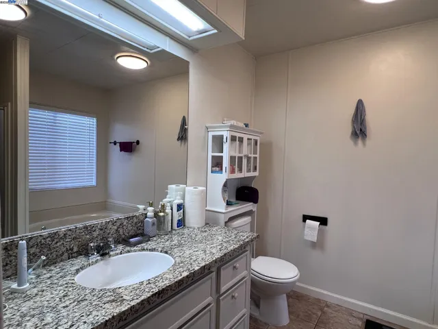 a bathroom with a granite countertop toilet sink and mirror