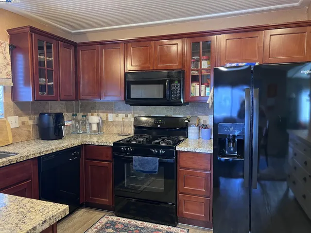 a kitchen with stainless steel appliances granite countertop wooden cabinets and a stove top oven