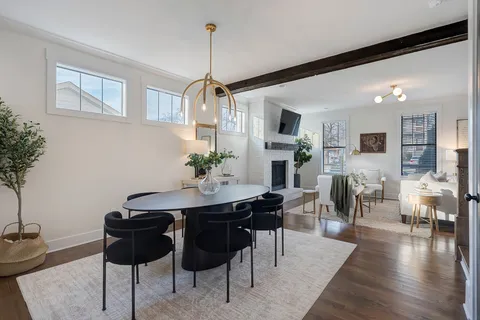 a view of a dining room and livingroom with furniture wooden floor a rug a potted plant and a chandelier
