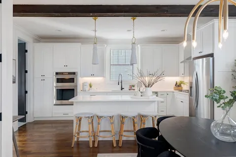 a kitchen with stainless steel appliances kitchen island granite countertop a table chairs in it and wooden floors