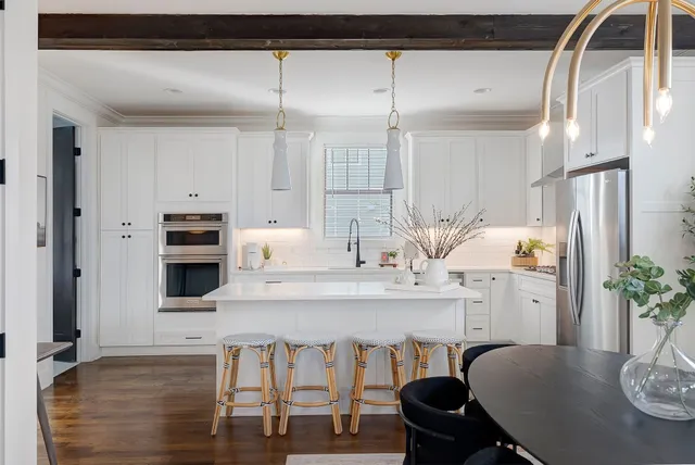 a kitchen with stainless steel appliances kitchen island granite countertop a table chairs in it and wooden floors