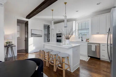 a kitchen with stainless steel appliances kitchen island granite countertop a table chairs sink and cabinets