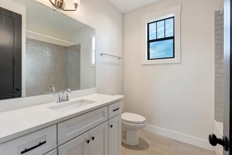 a bathroom with a toilet sink vanity and mirror