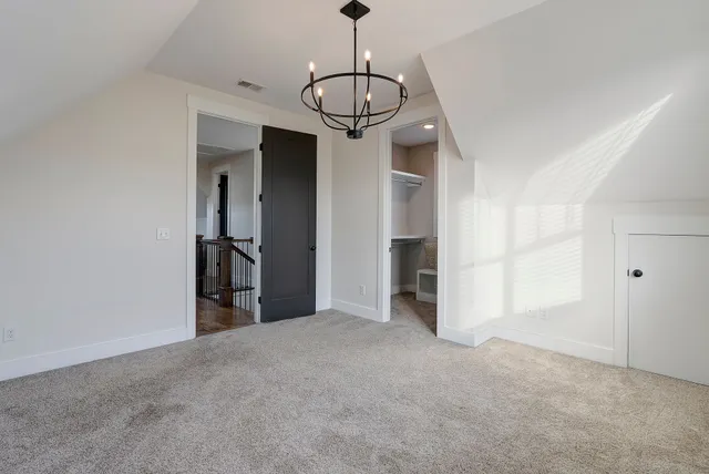 a view of a room with a hanging light and kitchen space