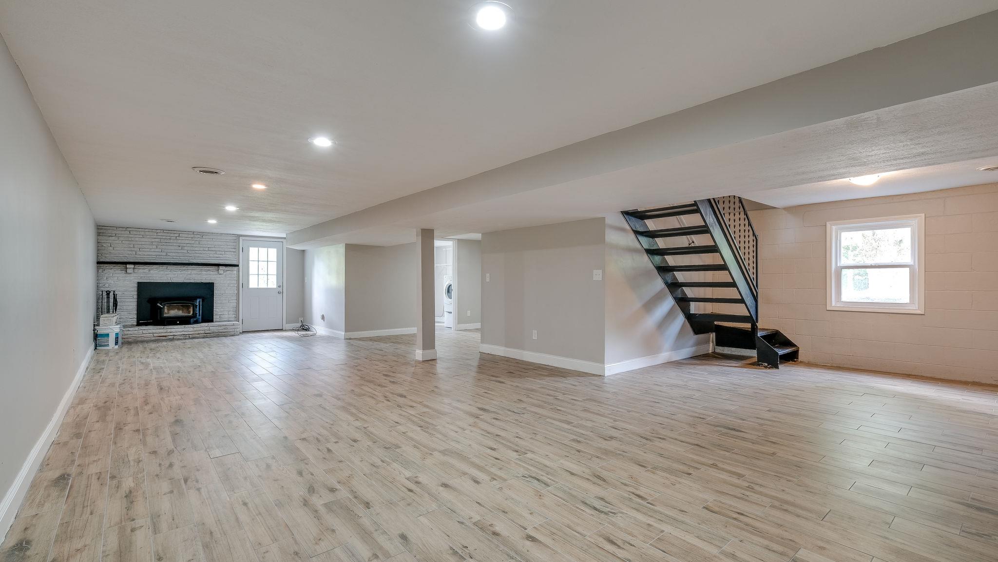 7373 Harper Road Joelton, TN 37080 - Photo 22 of 30 Sweeping basement w/new flooring installed by seller, wood burning stove is also new, installed by Ashbusters (paperwork available)~