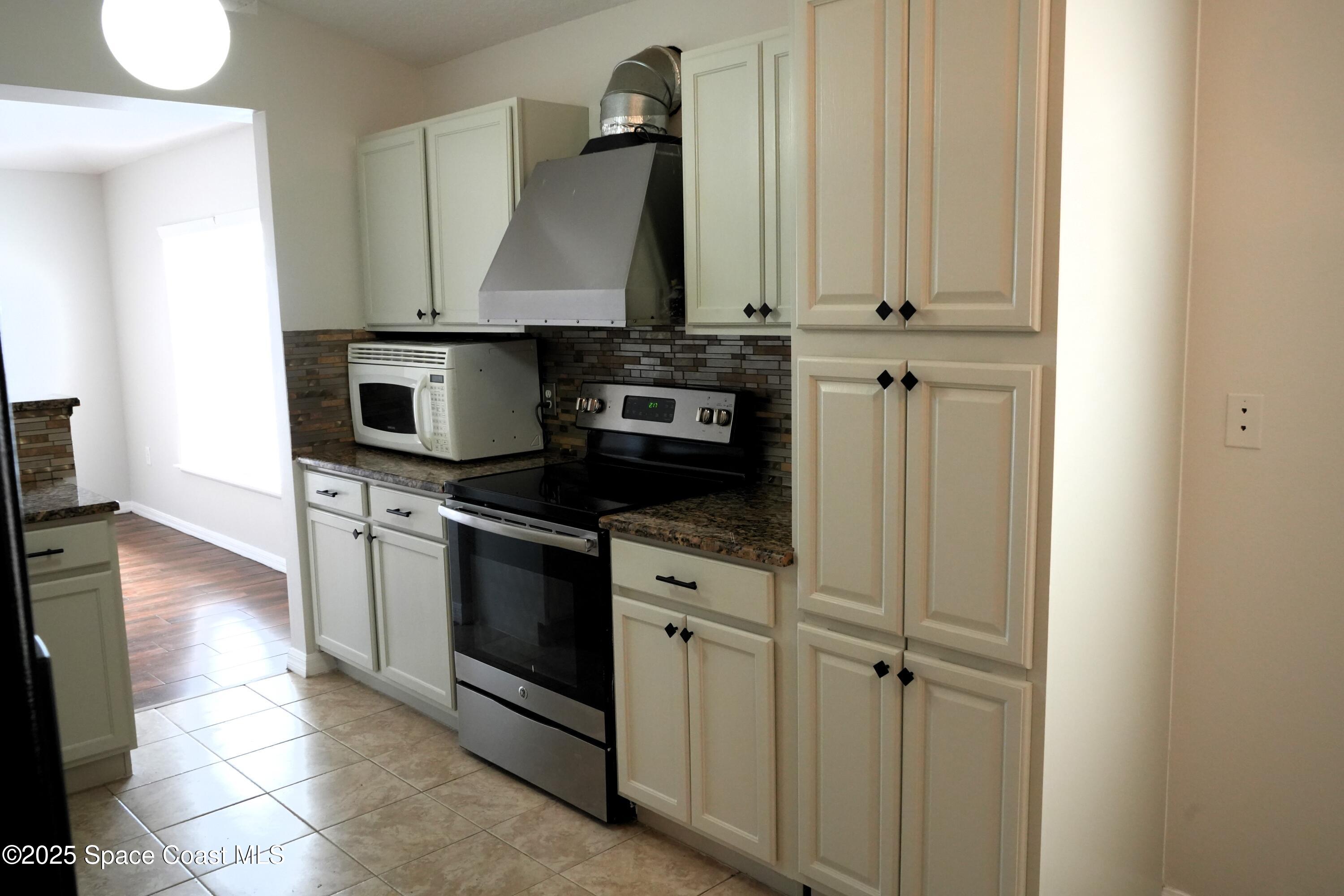 2125 Canopy Drive Melbourne, FL 32935 - Photo 2 of 18 a kitchen with stainless steel appliances granite countertop a stove a sink and a microwave