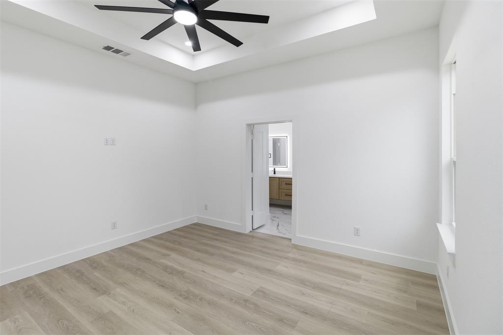 1119 Riverwood Road Dallas, TX 75217 - Photo 13 of 32 Empty room featuring a tray ceiling, light wood-style flooring, and ceiling fan