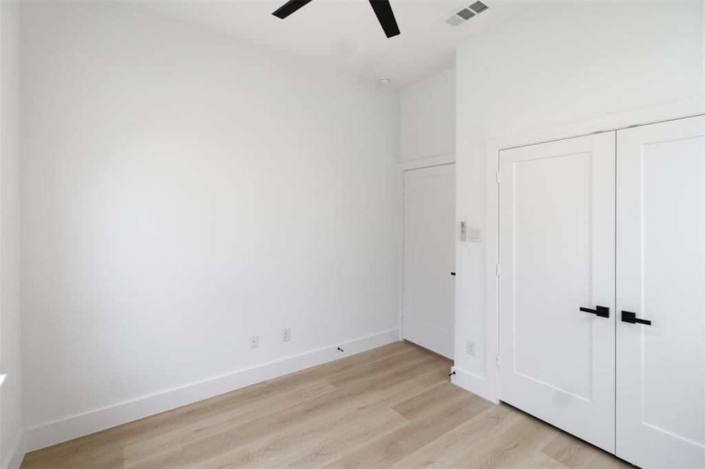 1119 Riverwood Road Dallas, TX 75217 - Photo 18 of 32 Unfurnished bedroom featuring light wood-style floors, a ceiling fan, and a closet