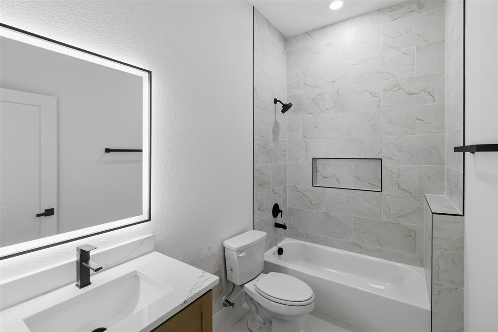 1119 Riverwood Road Dallas, TX 75217 - Photo 23 of 32 Full bath featuring vanity, a textured wall, and washtub / shower combination