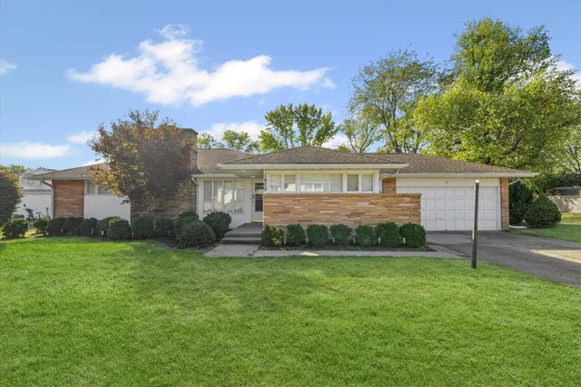 a view of a house next to a big yard and large trees