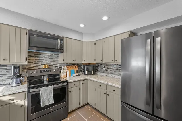 a kitchen with stainless steel appliances kitchen island granite countertop a refrigerator stove and sink