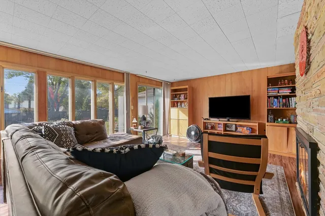 a living room with furniture a flat screen tv and a floor to ceiling window