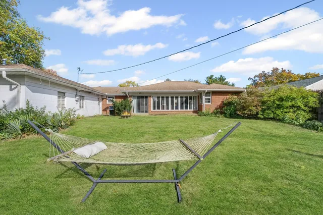 a view of a white house with a yard table and chairs