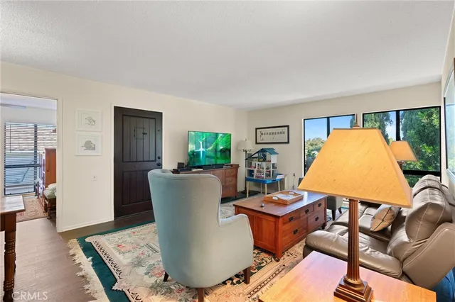 a living room with furniture a flat screen tv and floor to ceiling window