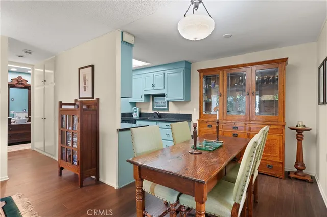 a kitchen with a stove a refrigerator and a dining table with wooden floor