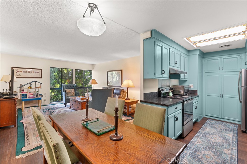 2121 Ronda Granada, Unit N Laguna Woods, CA 92637 - Photo 14 of 38 a kitchen with a stove a refrigerator and a dining table with wooden floor