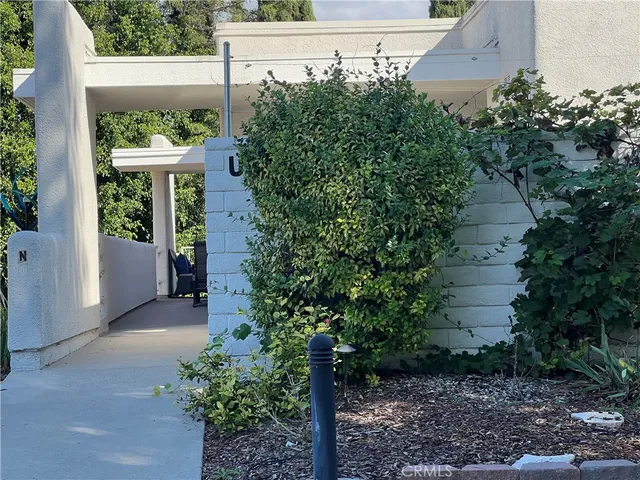 a view of a white house with a big yard and potted plants and trees