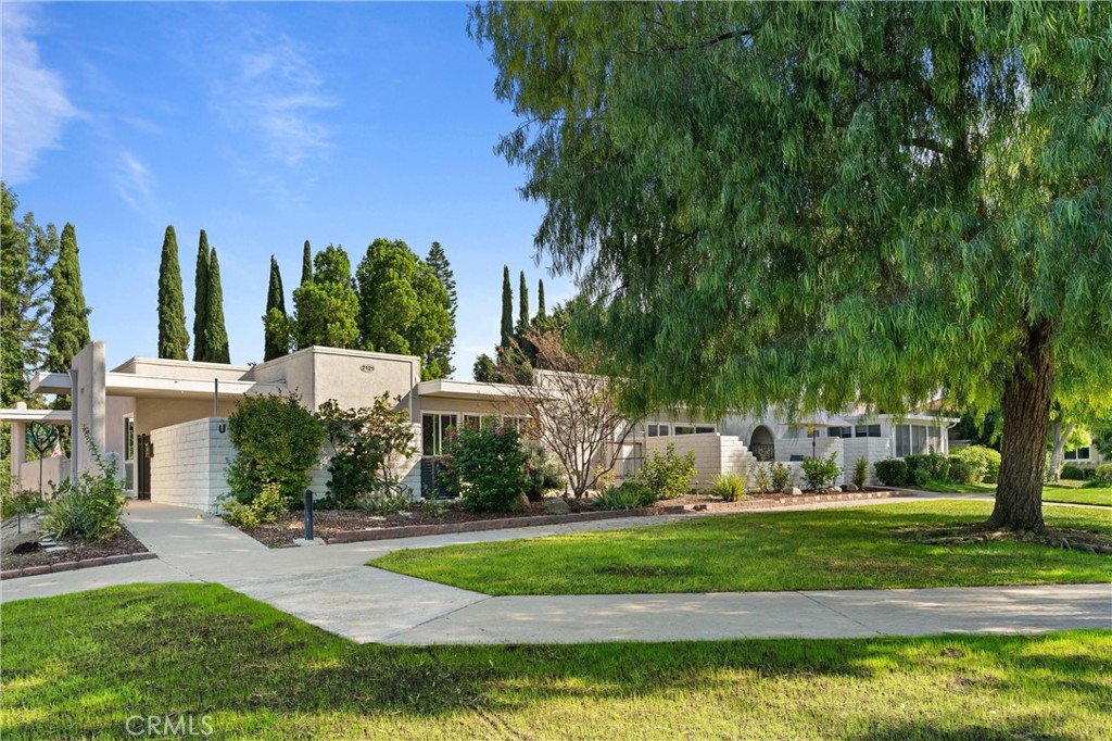 2121 Ronda Granada, Unit N Laguna Woods, CA 92637 - Photo 3 of 38 a view of a white house with a big yard and potted plants and trees