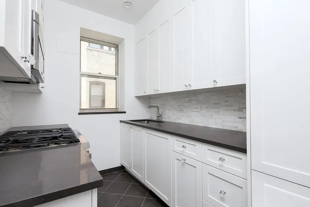 a kitchen with granite countertop white cabinets and a stove