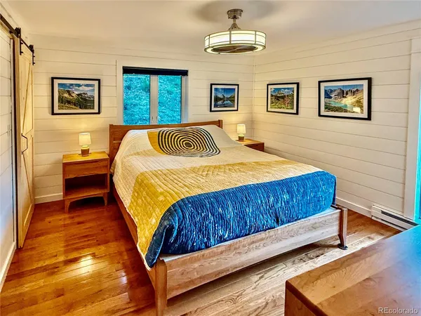 a bedroom with a large bed a window and painting on the wall