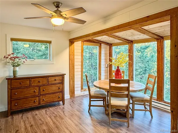 a dining room with wooden floor a chandelier a glass table and chairs