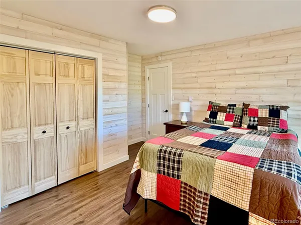a bedroom with a bed closet and a wooden floor