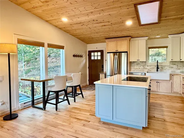 a kitchen with stainless steel appliances kitchen island granite countertop a table chairs and a large window