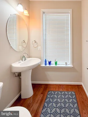 a view of a hallway with wooden floor and a bathroom