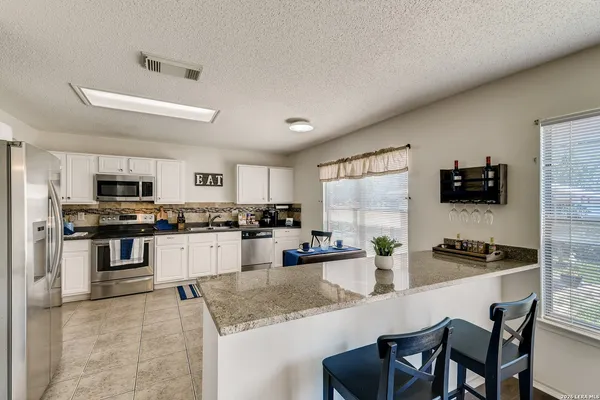 a kitchen with stainless steel appliances kitchen island granite countertop a stove top oven a sink a dining table and chairs
