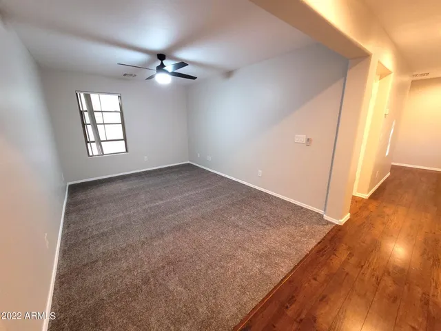 an empty room with wooden floor fan and windows