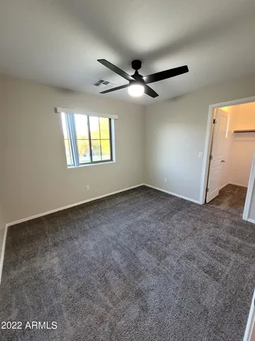 an empty room with windows and ceiling fan