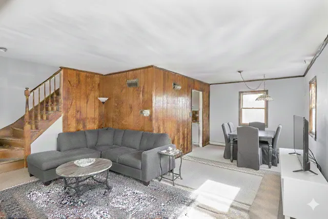 a living room with furniture and a dining table with rug