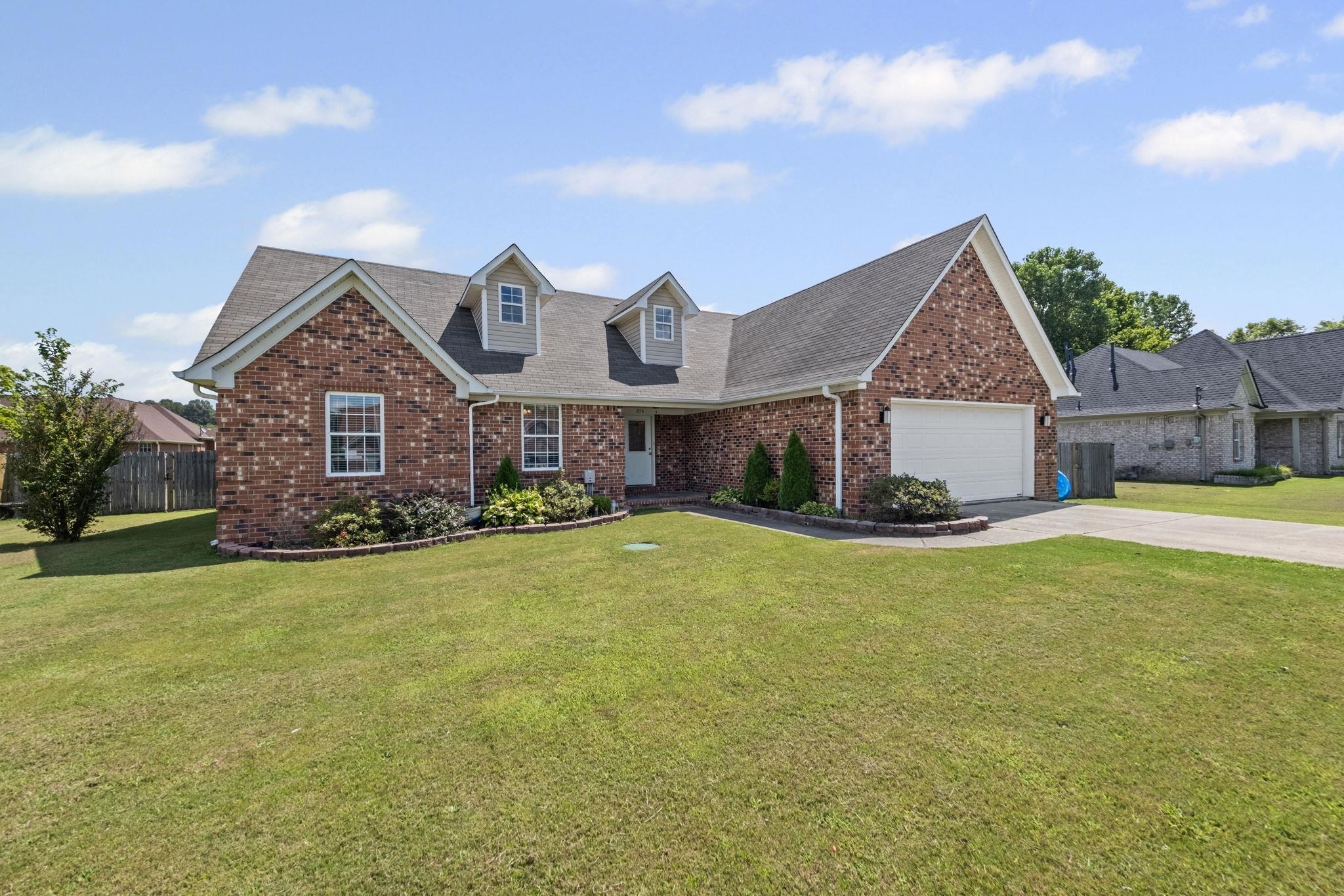 View of front of home featuring brick siding, driveway, a shingled roof, and an attached garage