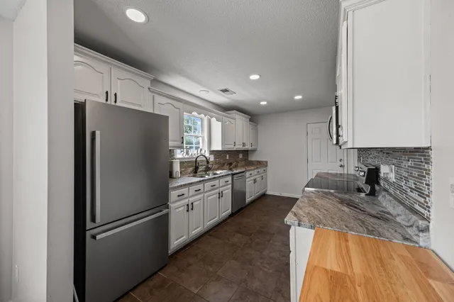 a kitchen with stainless steel appliances granite countertop a refrigerator a stove and a sink