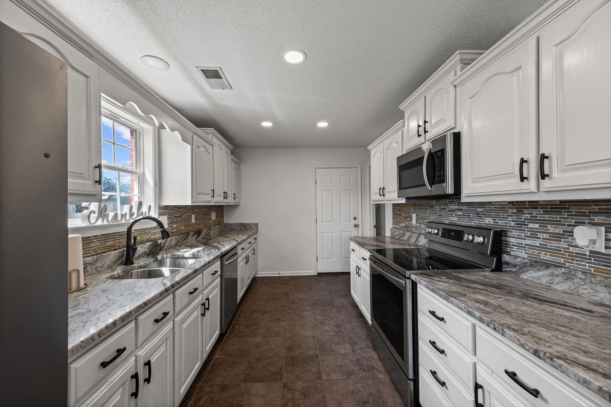 256 Azalea Drive Atoka, TN 38004 - Photo 14 of 39 Kitchen featuring stainless steel appliances, white cabinetry, light stone countertops, tasteful backsplash, and a textured ceiling