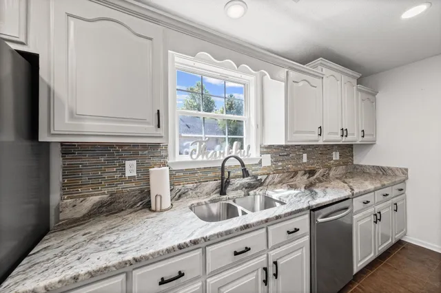 a kitchen with stainless steel appliances granite countertop a sink a stove and cabinets
