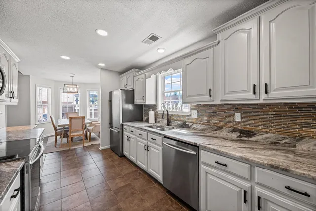a kitchen with stainless steel appliances granite countertop a refrigerator sink and cabinets