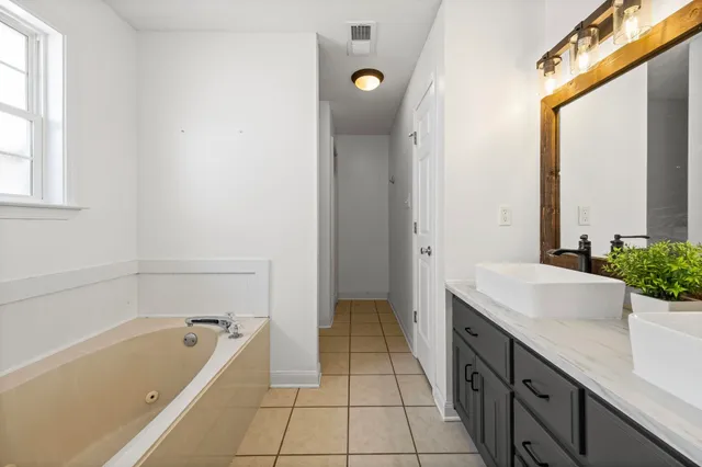 a spacious bathroom with a tub sink and mirror
