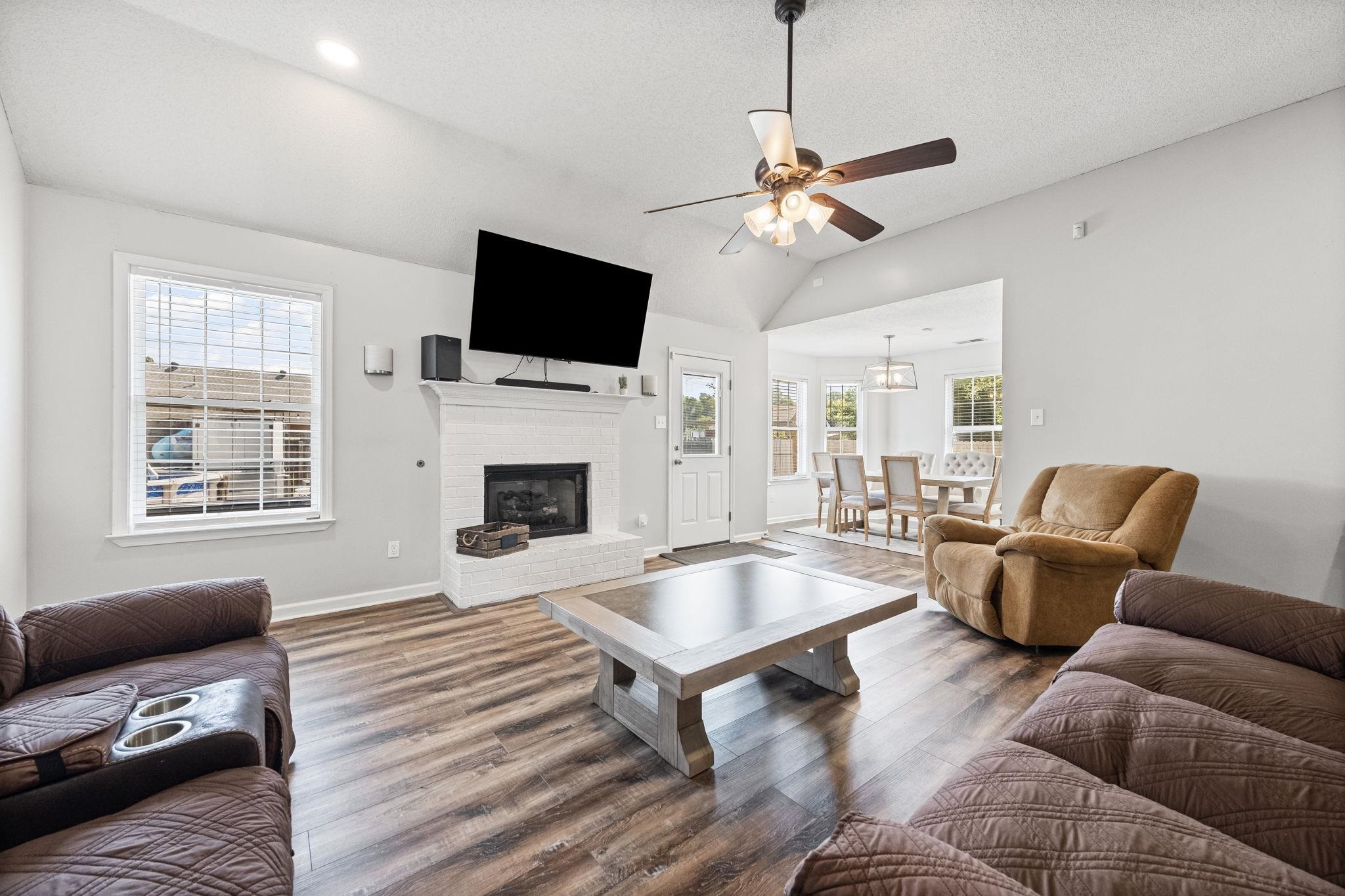 256 Azalea Drive Atoka, TN 38004 - Photo 7 of 39 Living room with plenty of natural light, wood finished floors, a brick fireplace, a ceiling fan, and vaulted ceiling