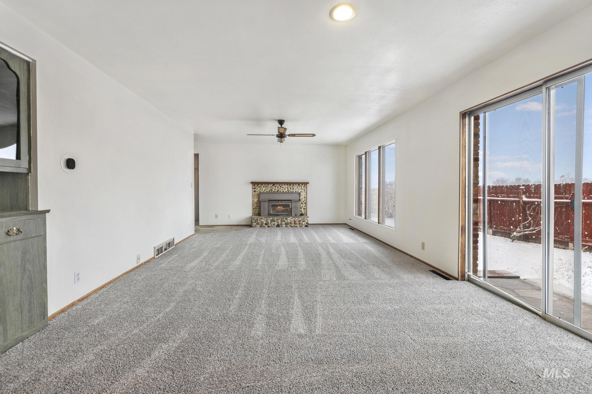409 Clear Lakes Road Buhl, ID 83316 - Photo 12 of 43 Unfurnished living room featuring a glass covered fireplace, carpet flooring, ceiling fan, and recessed lighting