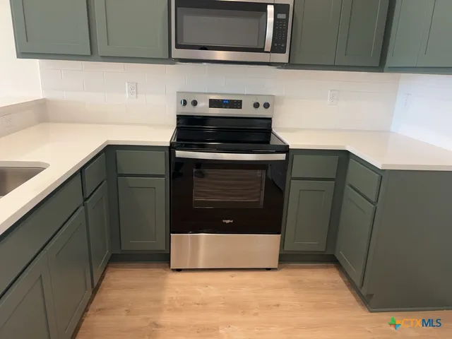 a kitchen with stainless steel appliances granite countertop a sink and a microwave