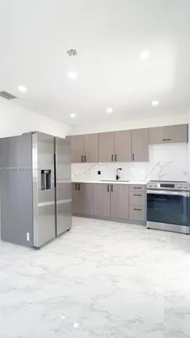 a large white kitchen with kitchen island a sink stainless steel appliances and cabinets