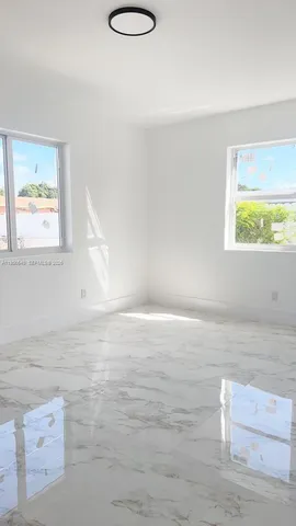 a view of empty room with window and wooden floor