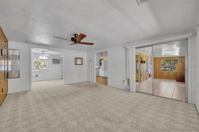 a view of an empty room with a window and a kitchen