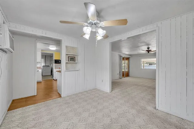 a view of a hallway with wooden floor and a kitchen