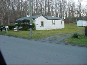 a front view of a house with a garden and trees