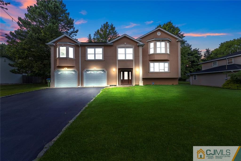a front view of a house with a yard and green space
