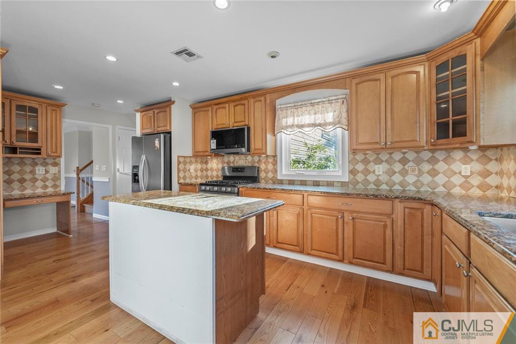 33 Hazel Avenue Edison, NJ 08820 - Photo 9 of 52 a kitchen with kitchen island granite countertop wooden floors and stainless steel appliances