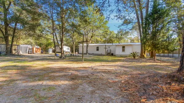 a view of a house with a big yard and large trees